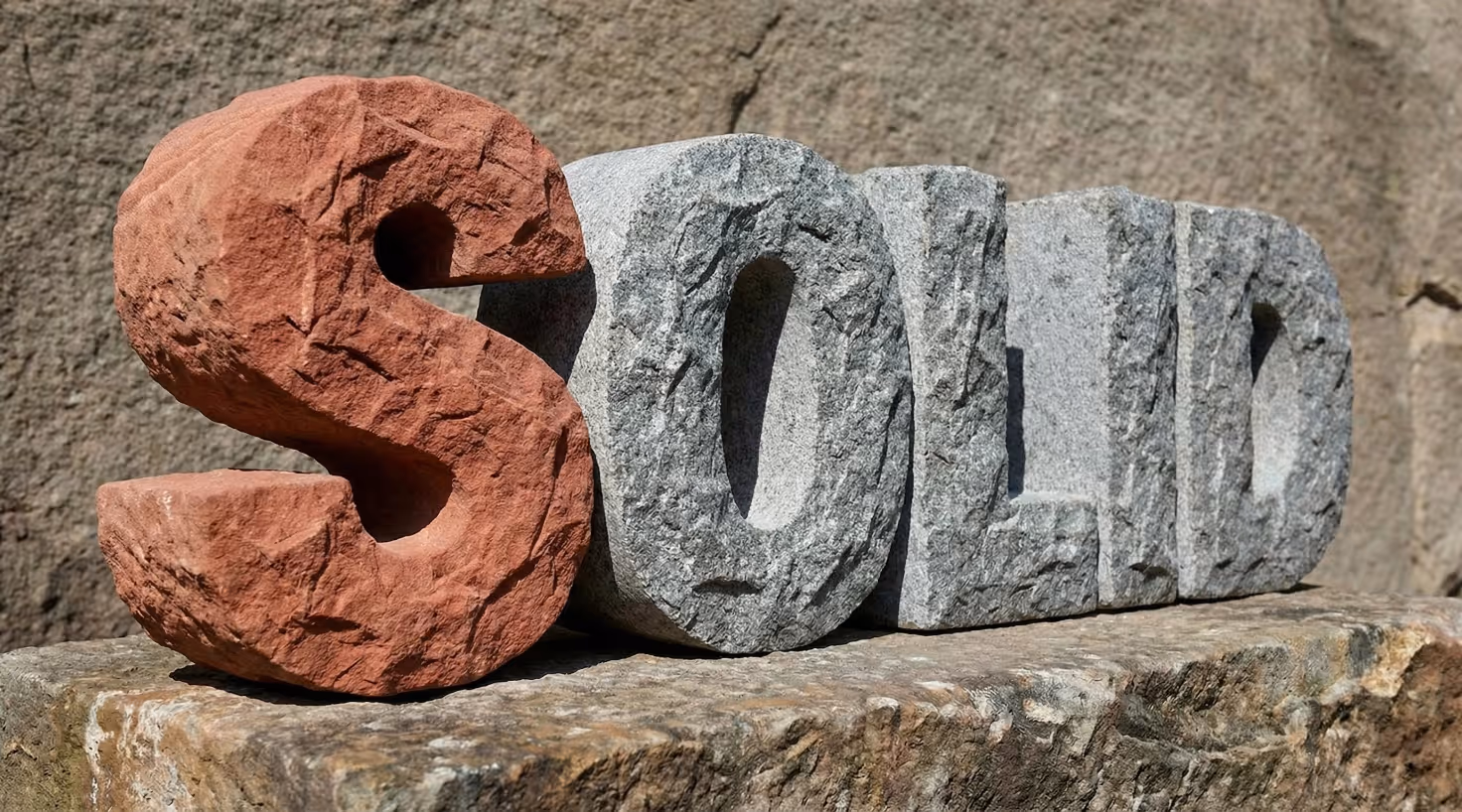 La palabra 'SOLID' esculpida en grandes letras de piedra rugosa, con la letra 'S' resaltada en rojo.